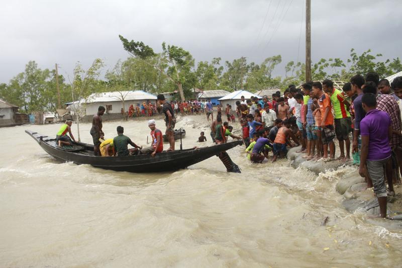 A boat brings people to land, as locals check an embankment before Cyclone Amphan made landfall, in Shyamnagar, Shatkhira, Bangladesh, Wednesday, May 20, 2020. Photo: AP